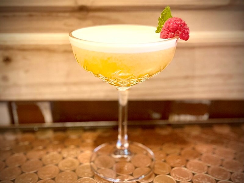 A yellow cocktail on a table.