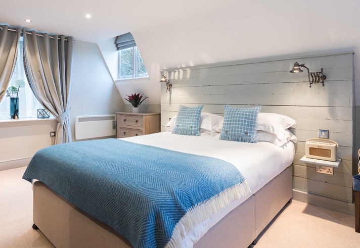 Elegant bedroom at The Florentine featuring a neatly made bed with a blue throw and contemporary décor.