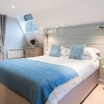 Elegant bedroom at The Florentine featuring a neatly made bed with a blue throw and contemporary décor.