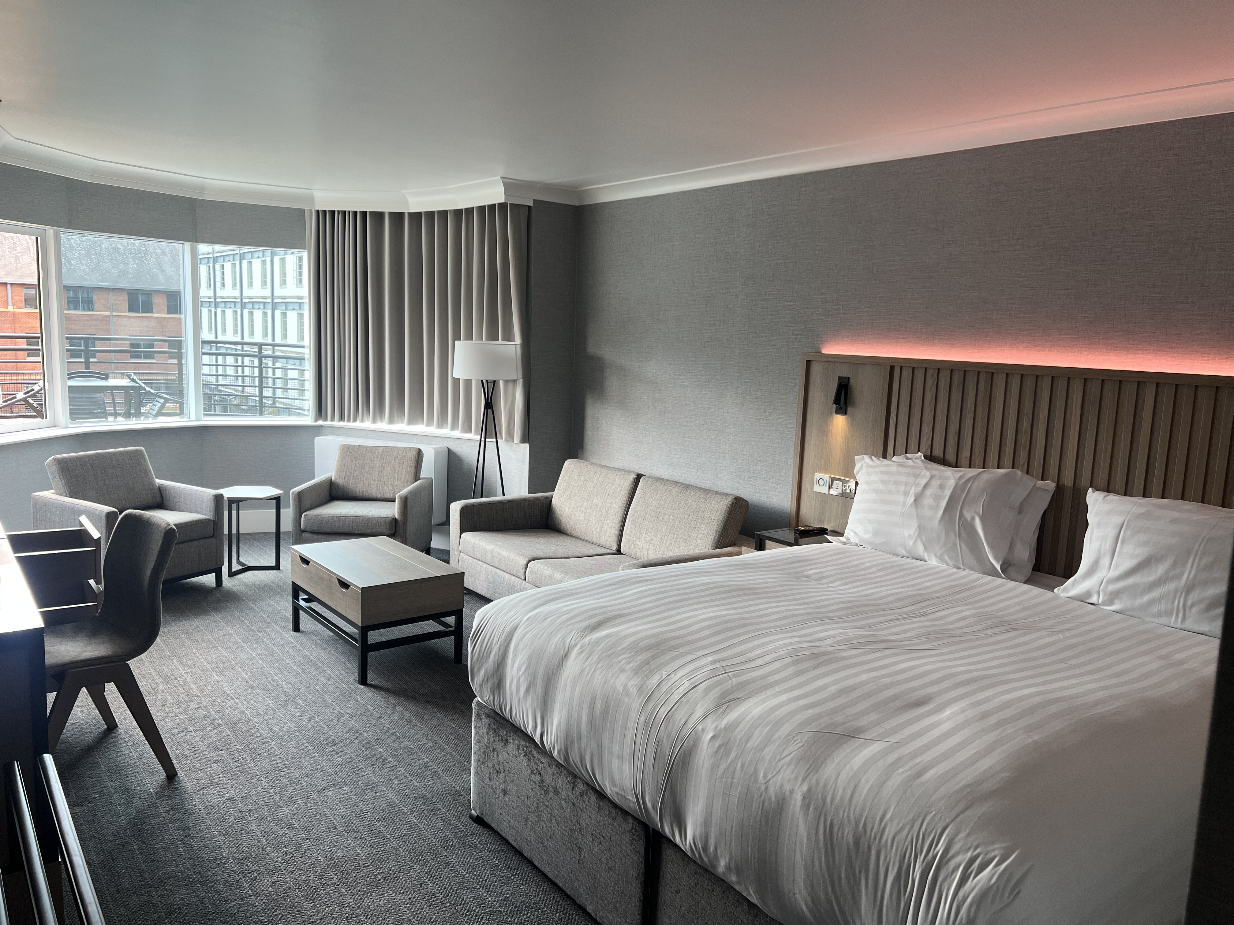 Modern double bedroom with seating area and ambient mood lighting.