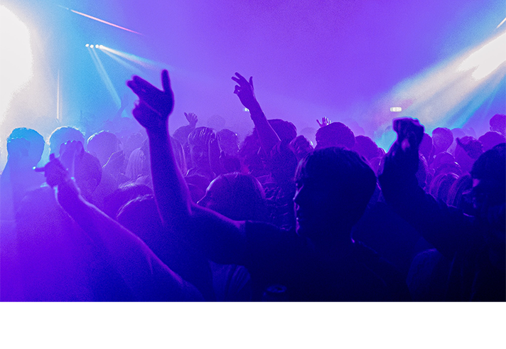 A huge crowd dancing to club music in moody blue lighting.