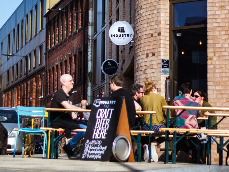 People sat at tables outside The Industry Tap.