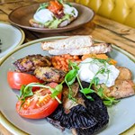 Three plates of food on a wood table in a booth.