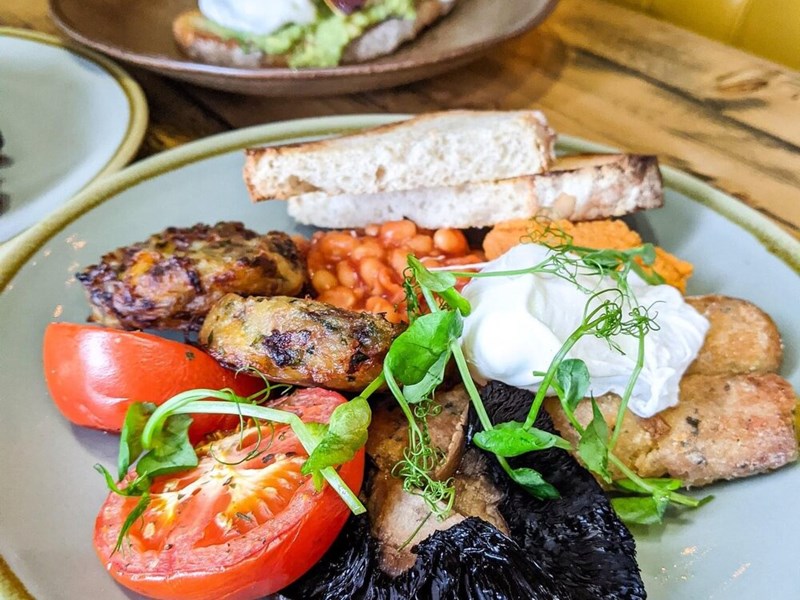 Three plates of food on a wood table in a booth.