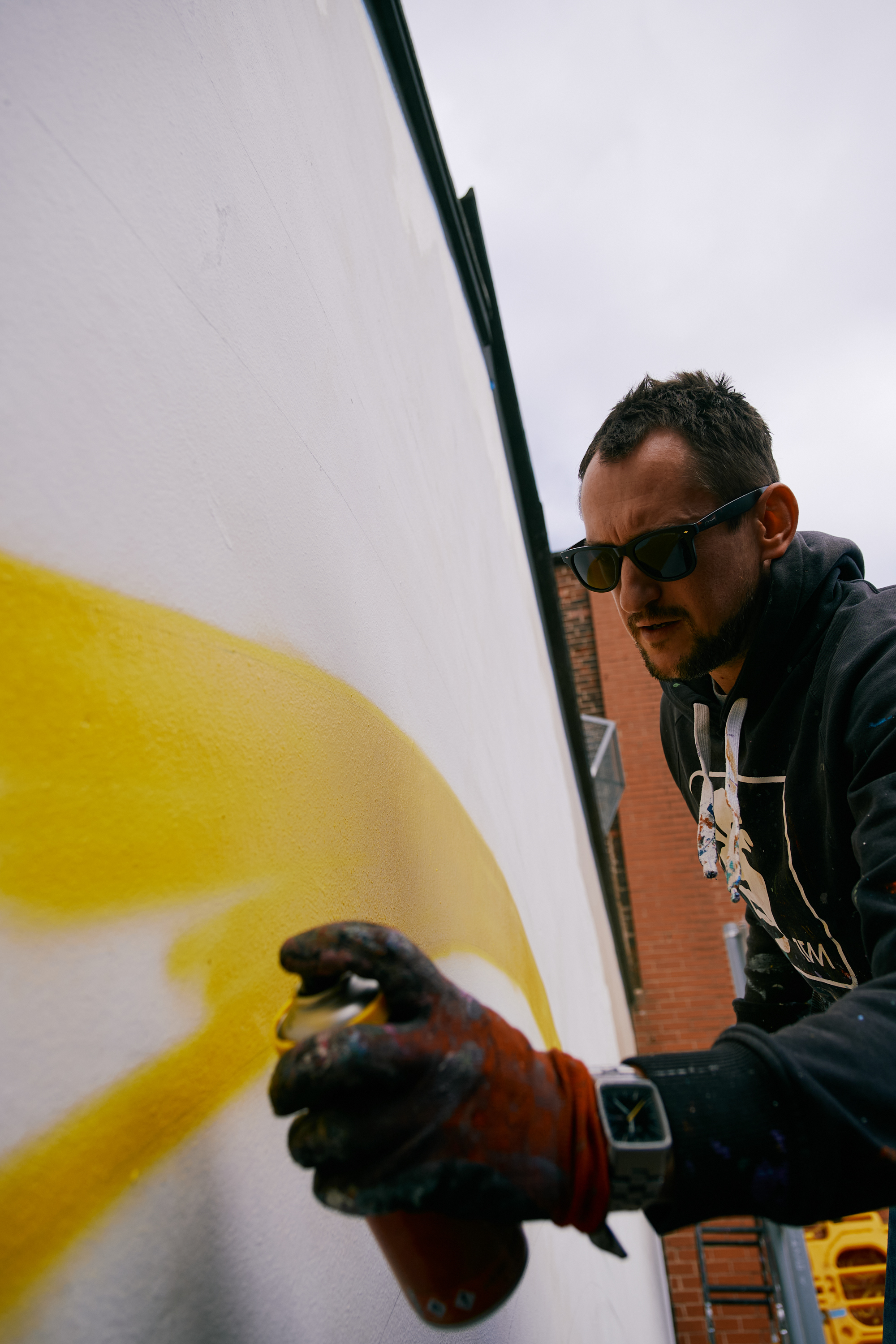 A man spray-painting a mural on a wall.