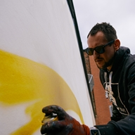 A man spray-painting a mural on a wall.