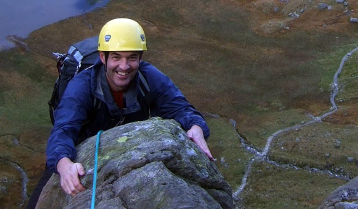 A man smiles as he reaches the top of a climb.