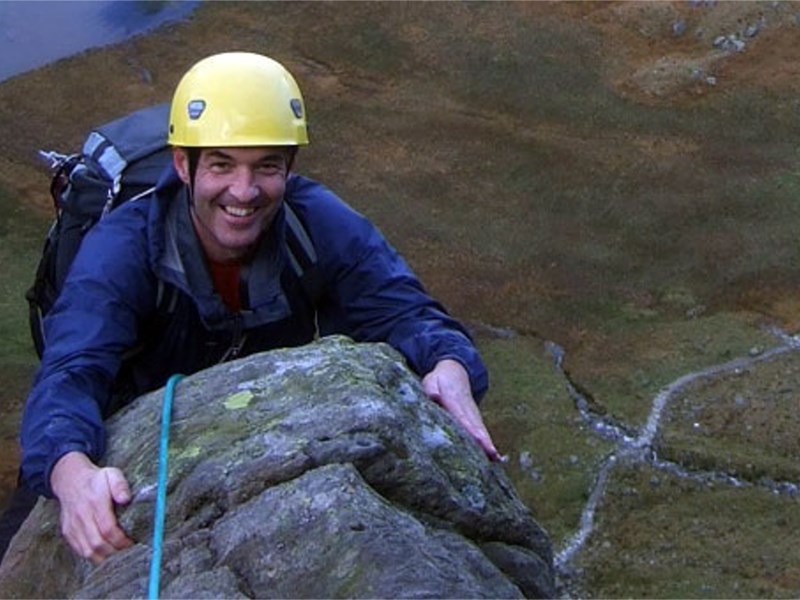 A man smiles as he reaches the top of a climb.