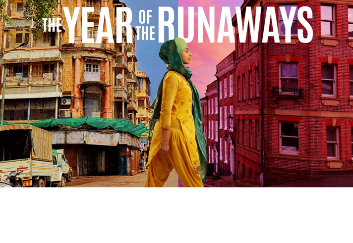 A young woman walks between two worlds, one side of the street depicts India and the other side, Sheffield.