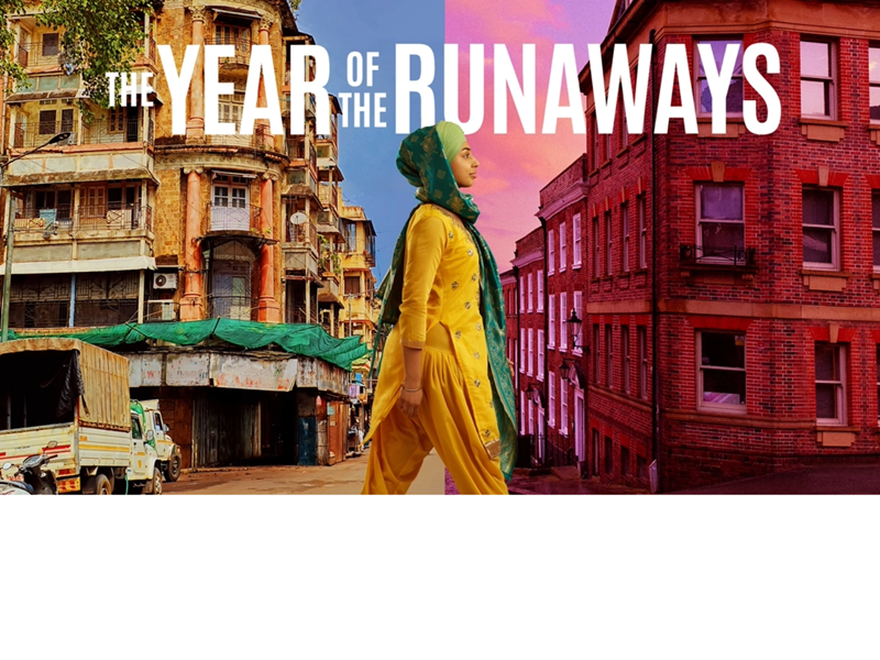 A young woman walks between two worlds, one side of the street depicts India and the other side, Sheffield.