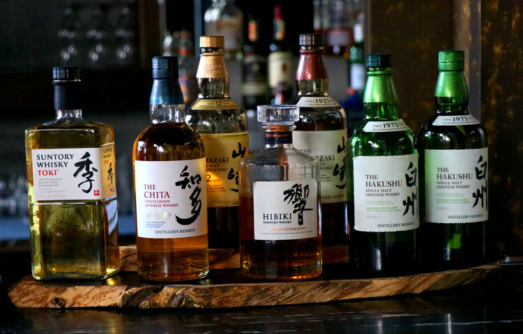 A row of bottles on a bar with Japanese text on them.