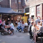 The courtyard at Yellow Arch filled with people standing and sitting at tables.