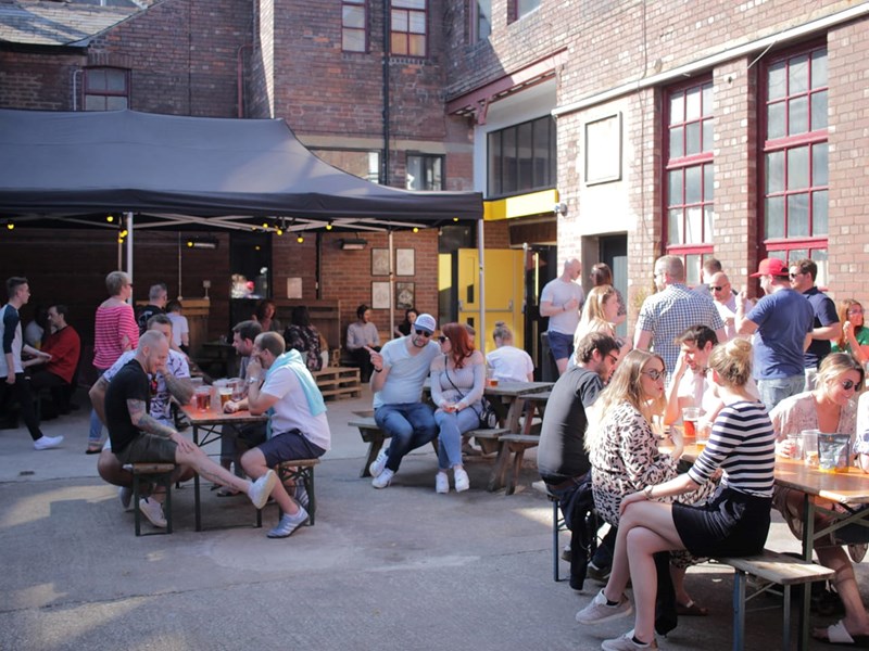 The courtyard at Yellow Arch filled with people standing and sitting at tables.