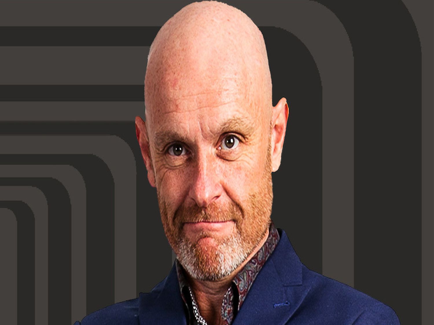 A person wearing a dark blue blazer and a patterned shirt stands against a black background featuring a series of concentric rounded rectangles in a lighter shade of gray, creating a modern, graphic design effect.