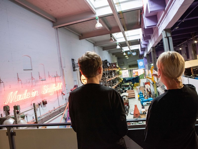 two people stood on a walkway looking down into Kelham Island Museum.