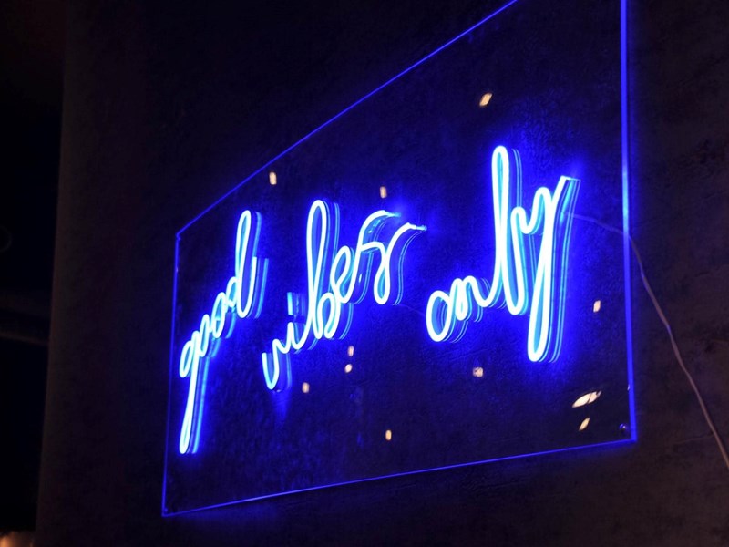 A blue neon sign that reads 'Good vibes only' on the wall at Sheffield Plate.