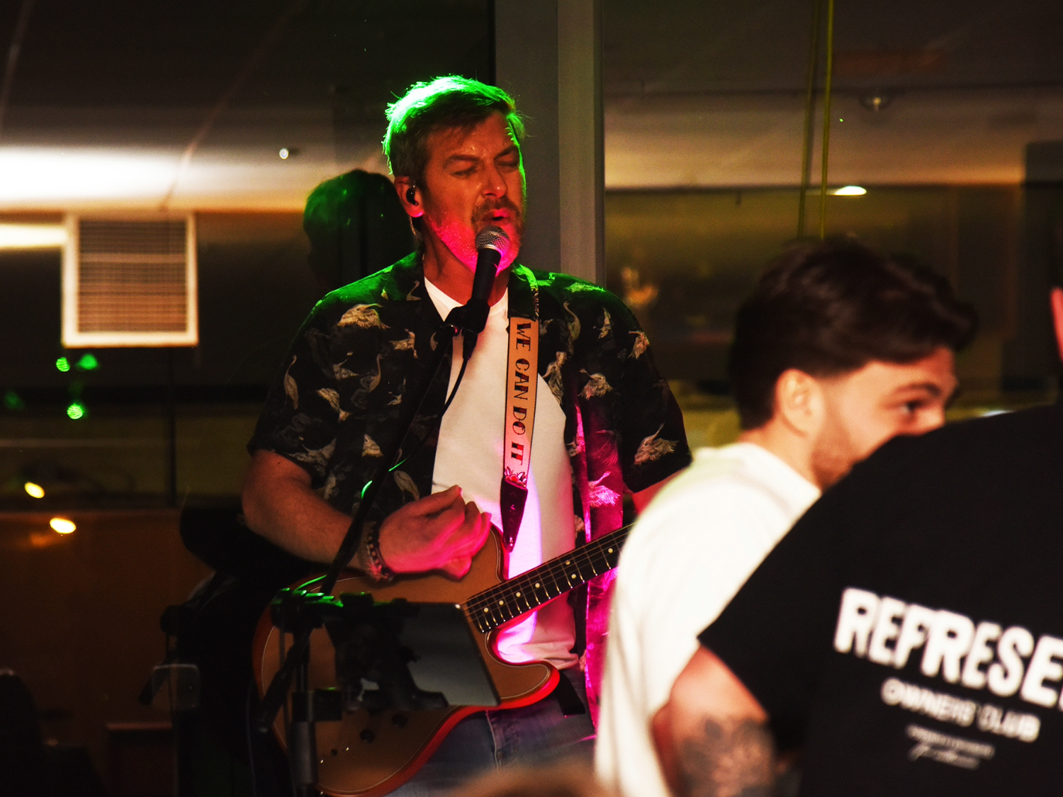 A man is singing and playing a guitar to a crowd.