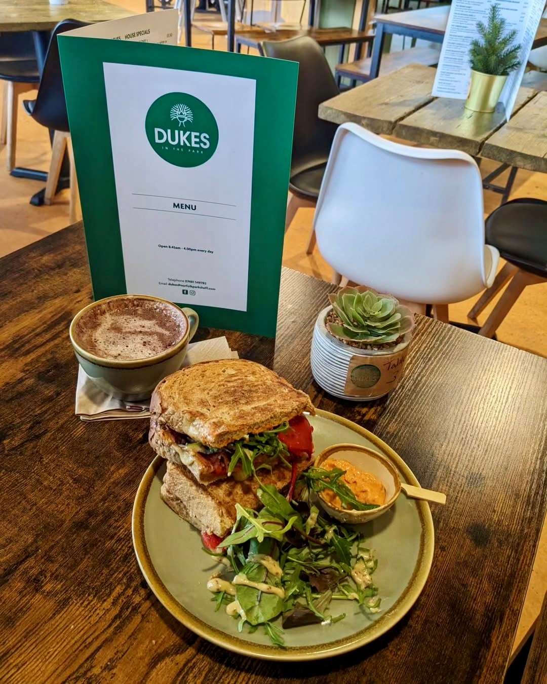 A tempting toasted sandwich on a table with a cappuccino 