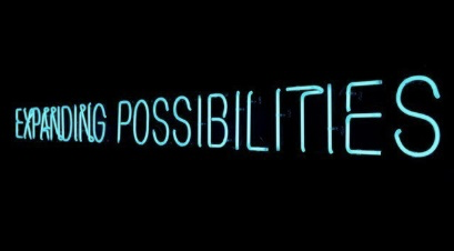 A blue neon sign reading 'expanding possibilities' on a dark background.