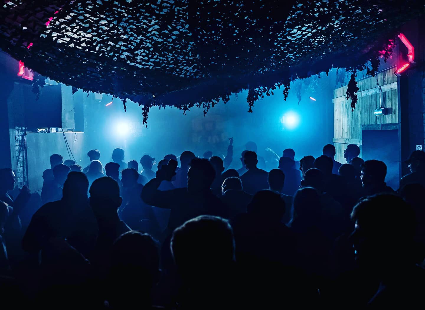 A blur-lit venue full of people dancing.