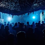 A blur-lit venue full of people dancing.