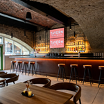 The bar at Tavern on The Quays, with the vaulted stone ceiling plus bar stools lined up along the bar and tables and chairs in the foreground.