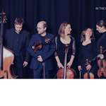 Members of Ensemble 360 in a relaxed photograph, holding their instruments and chatting and laughing.