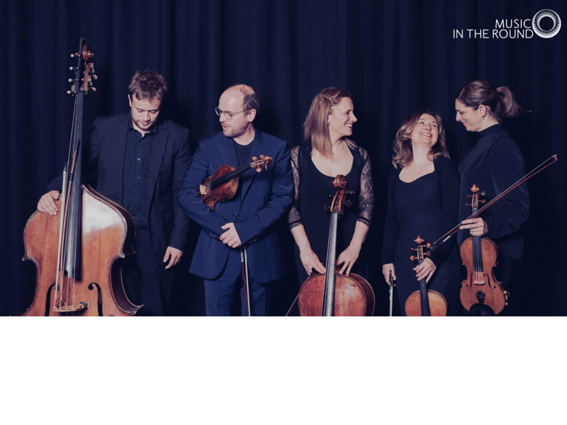 Members of Ensemble 360 in a relaxed photograph, holding their instruments and chatting and laughing.
