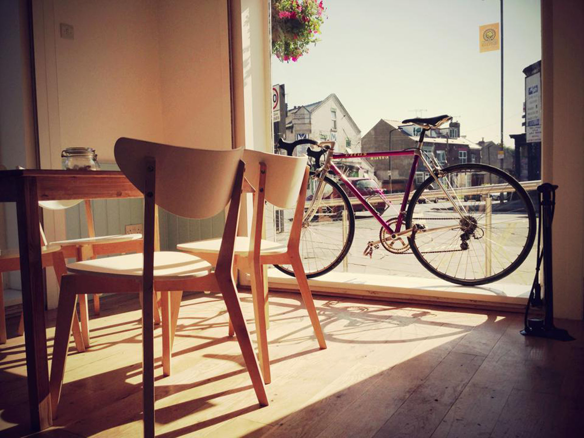 Simple but lovely wooden table and chairs at Amici & Bici. Outside a bike leans against the window.