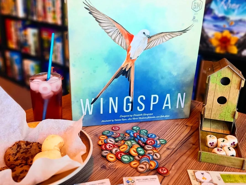 A table at The Dice Box Sheffield, with cakes and a drink and a game called Wingspan.
