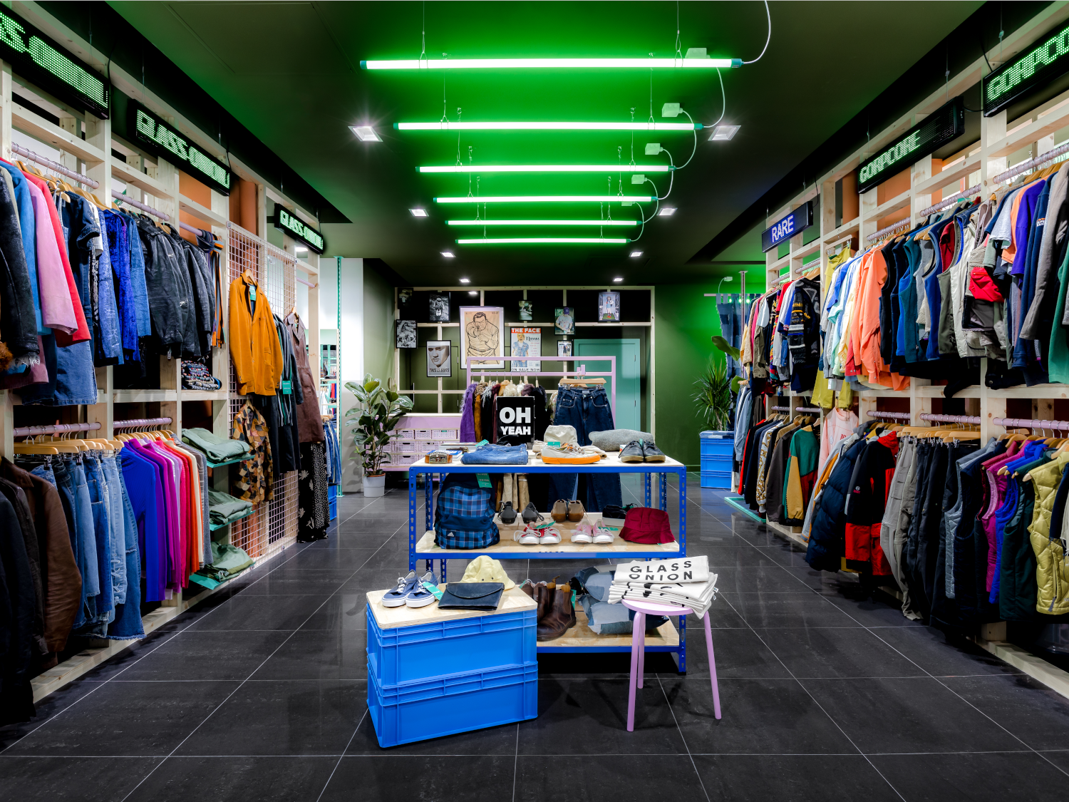 Inside the Glass Onion shop. All the walls are full of clothes on rails. In the centre of the shop are tables with accessories on display.