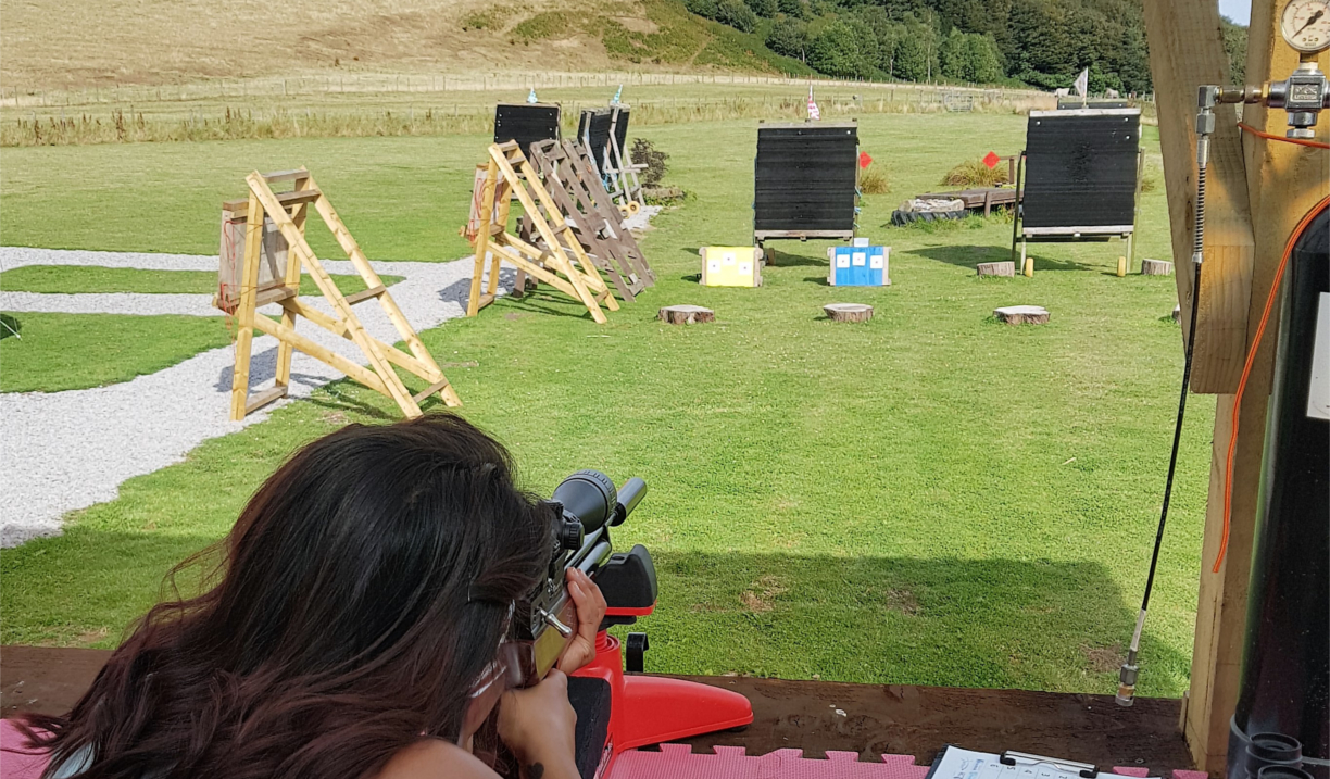 A person aiming a rifle at a target on a shooting range.