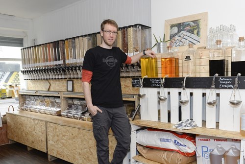 A man is stood in a shop next to a row of produce dispensers.