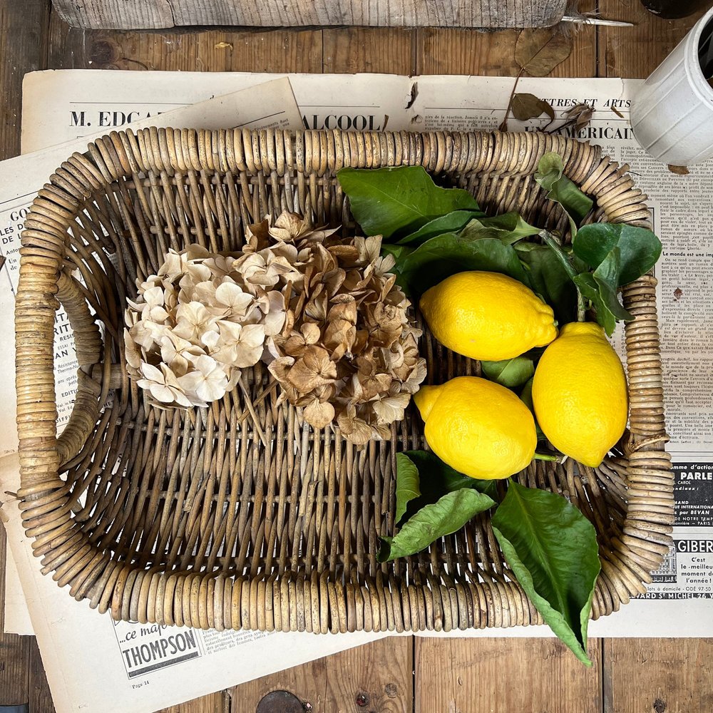 A hand basket with dried flowers and lemons in it.