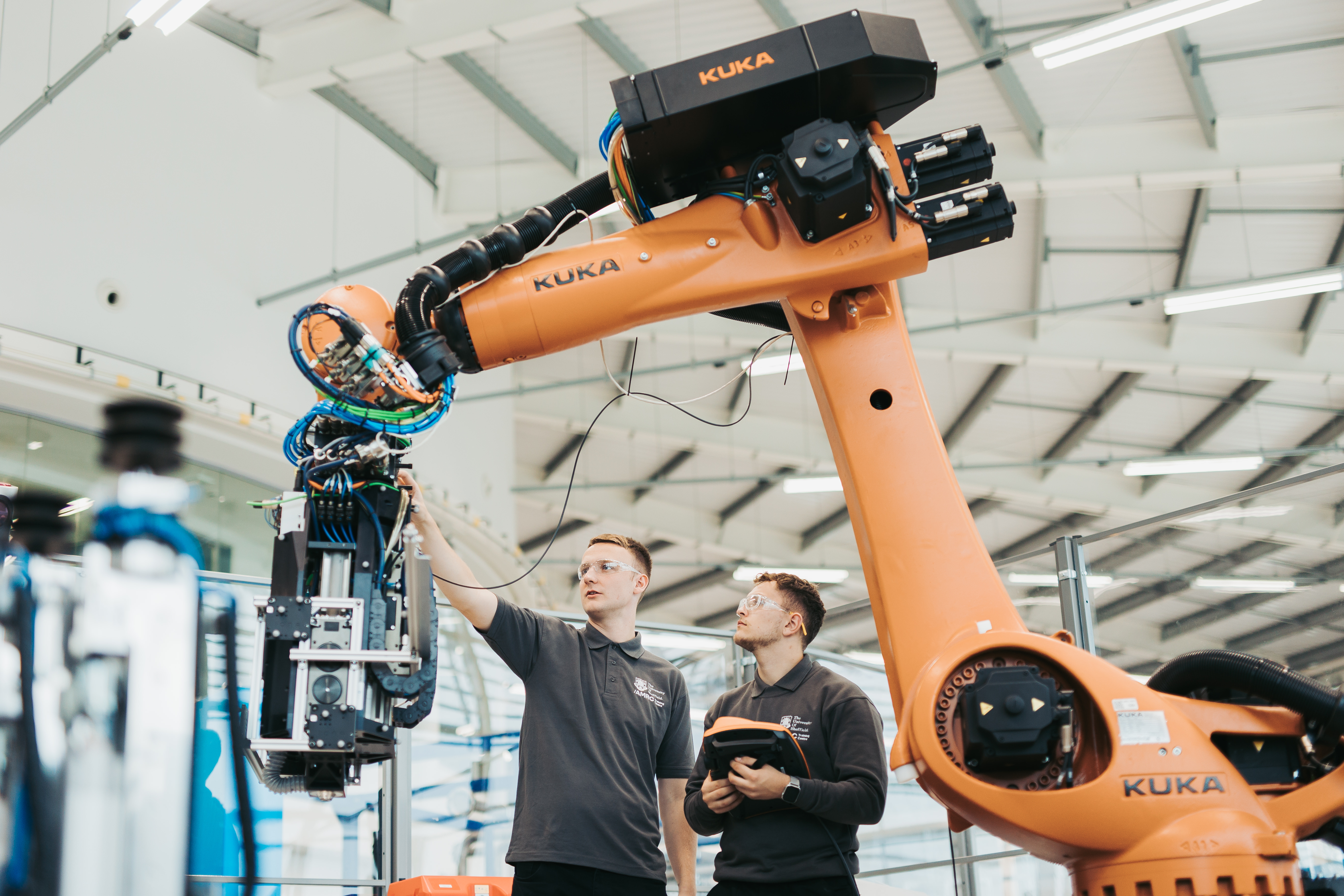 Two people are working on a large robot arm.