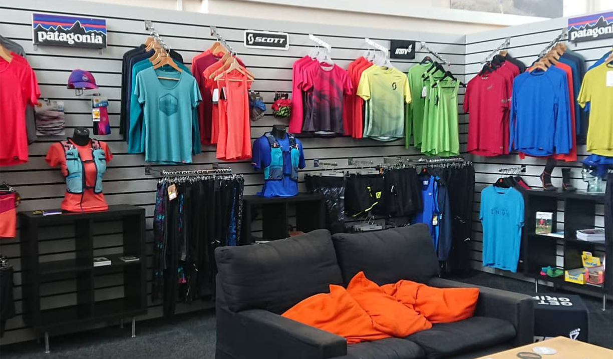 The interior of a shop, with lots of sporting clothes, shoes and equipment on display.