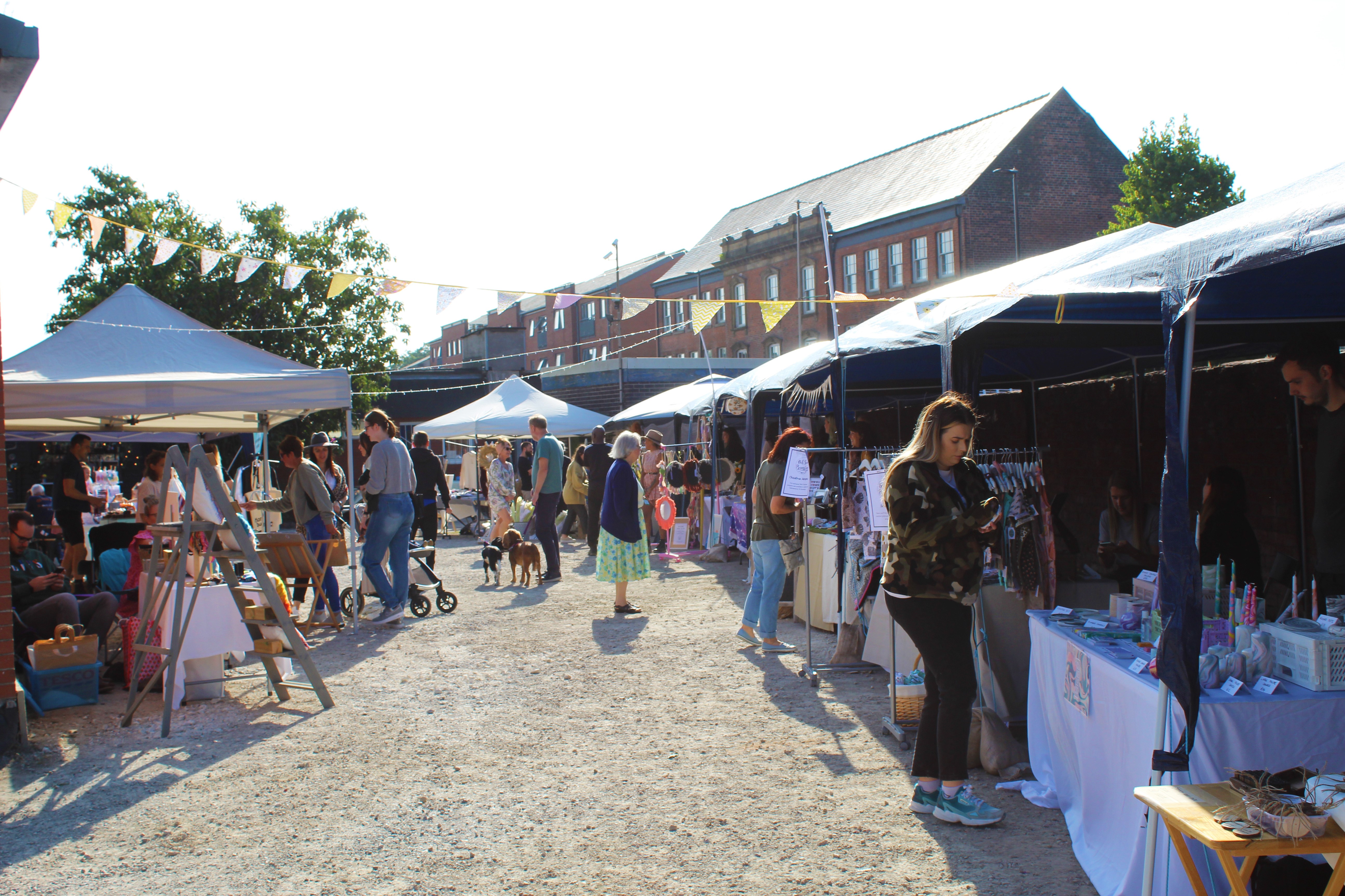 People looking through the stalls at Rex Market on a sunny day.
