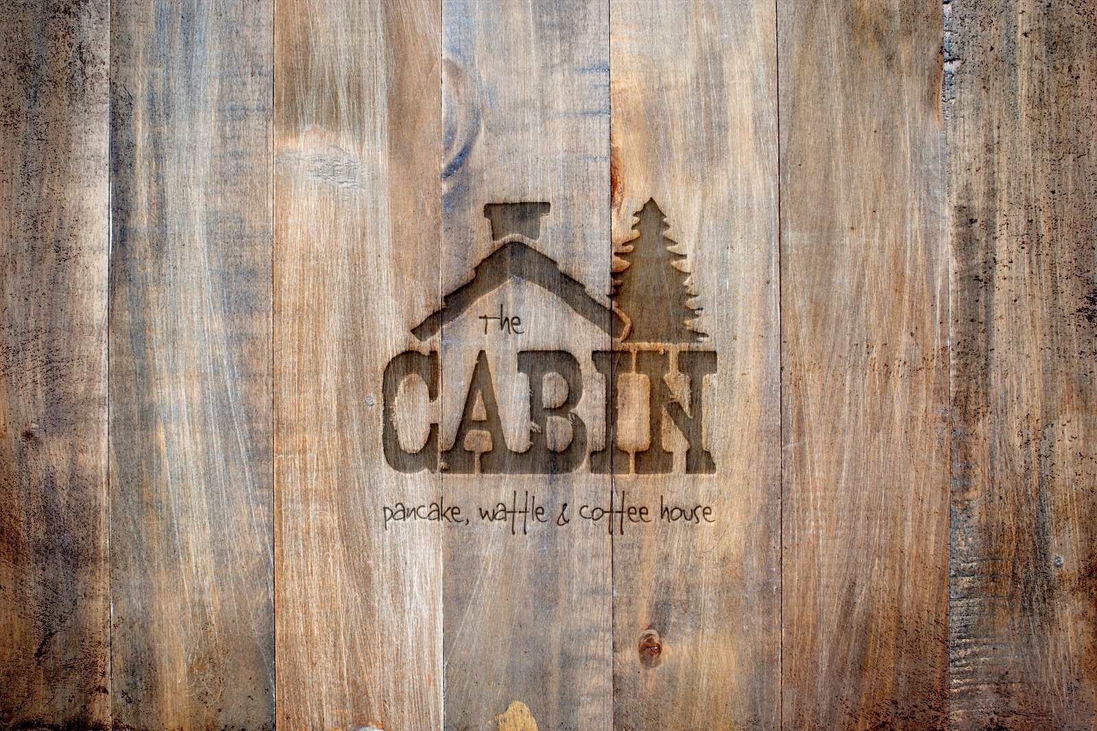 The Cabin logo on a wooden wall.