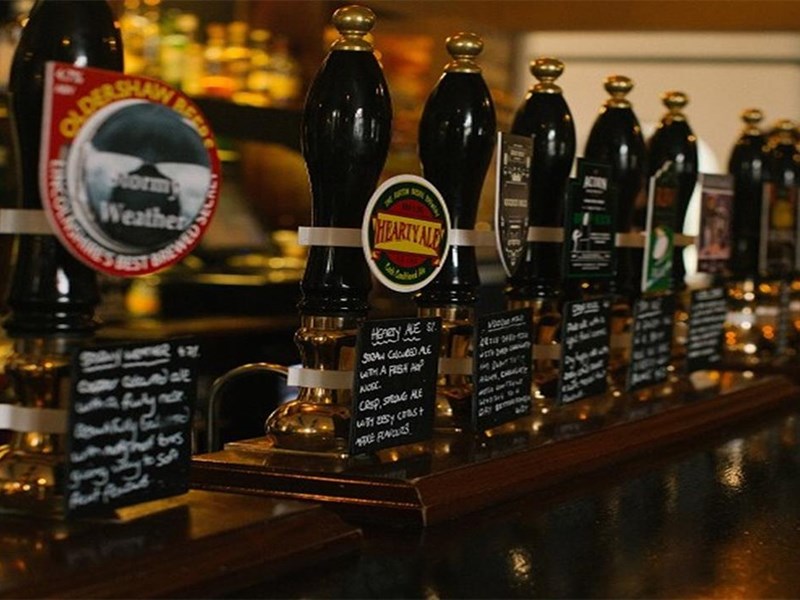 A row of beer taps on a traditional pub bar.
