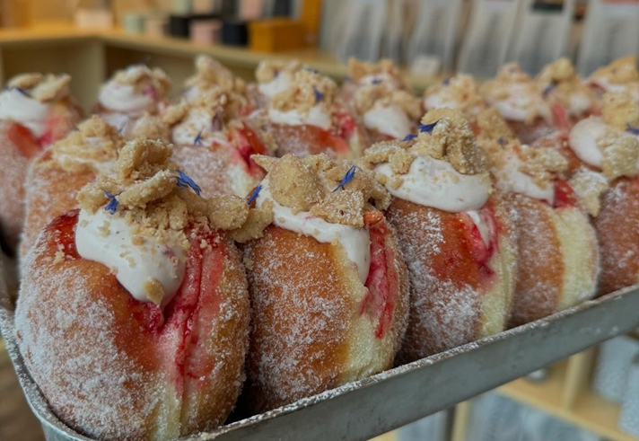 A tray of doughnuts filled with jam and cream.