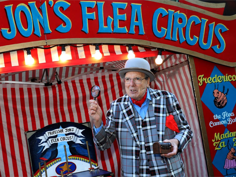 A man dressed as an old fashioned travelling showman presents Jon's Flea Circus.