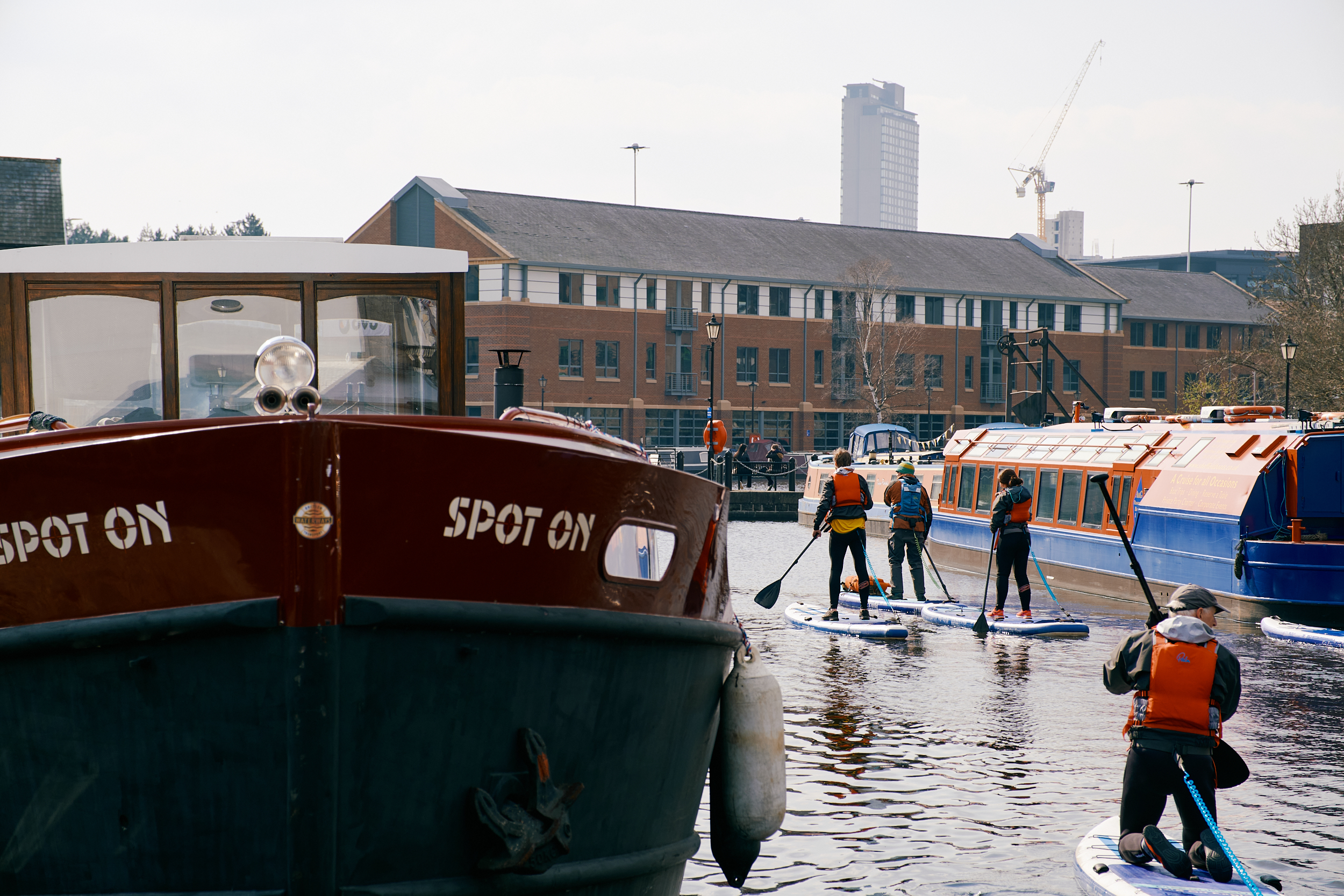 Four people stand up paddle boarding on the canal at Victoria Quays, Sheffield.