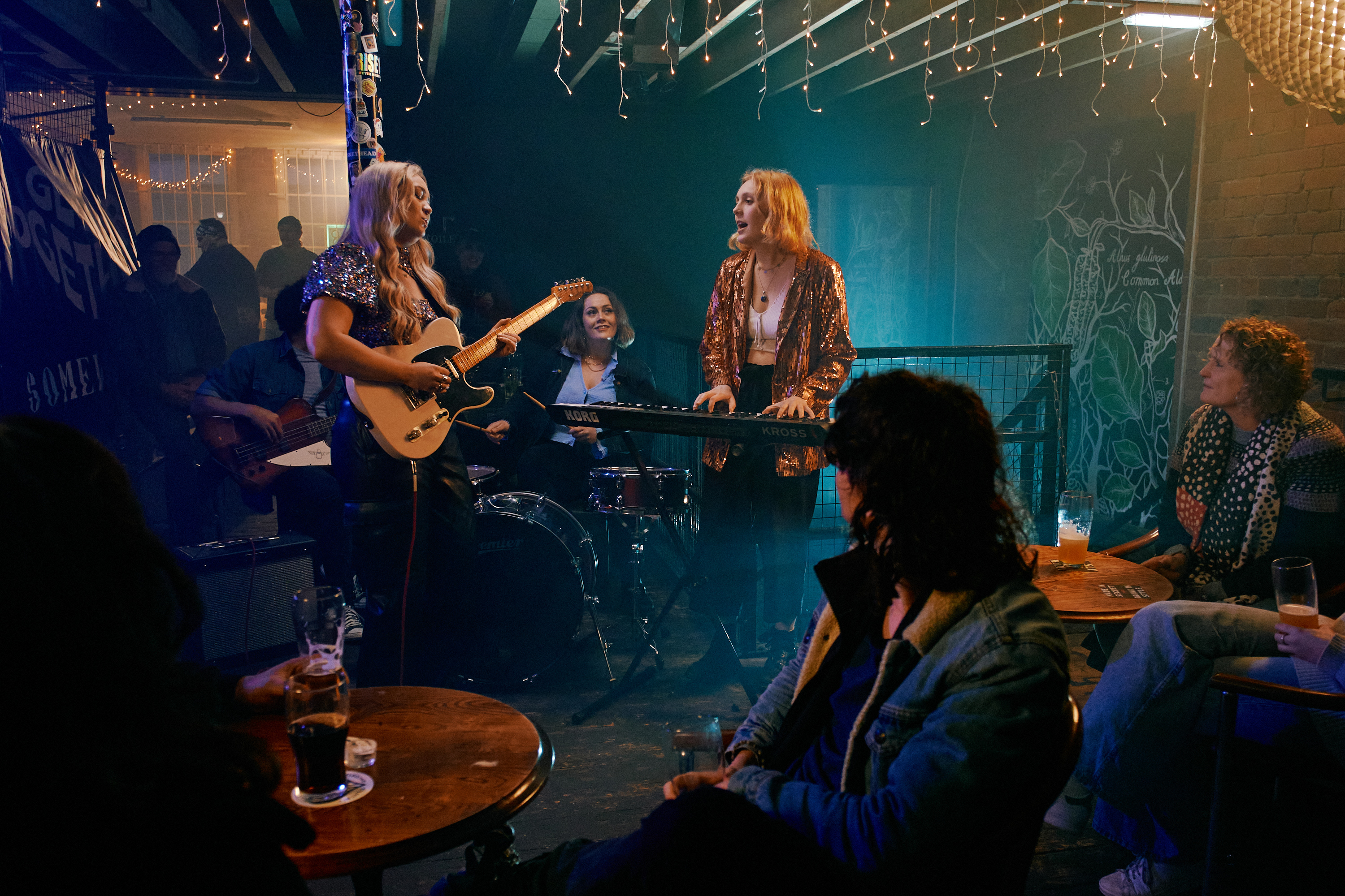 A three piece band plays live in front of a crowd at Alder.