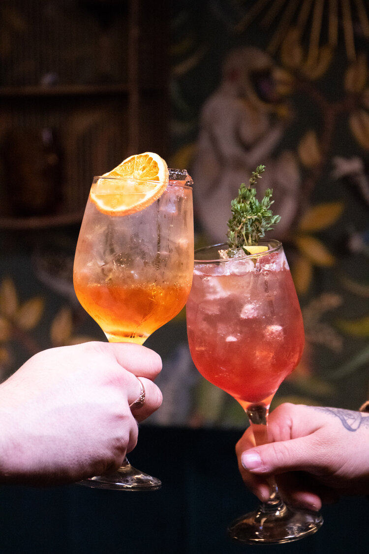 Two cocktails being held. 