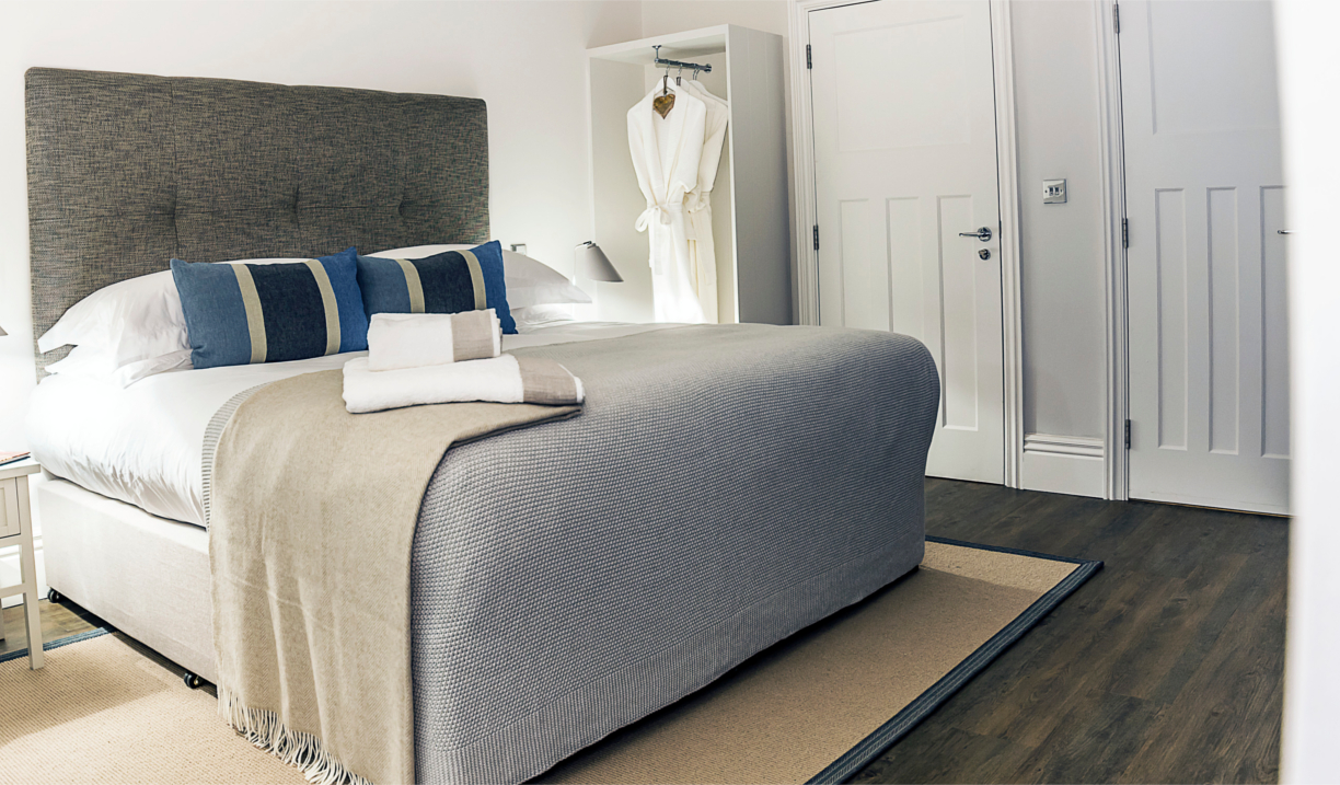 Beautiful double bed with soft furnishings in light, neutral colors and decorative cushions.