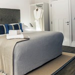 Beautiful double bed with soft furnishings in light, neutral colors and decorative cushions.