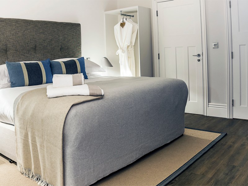 Beautiful double bed with soft furnishings in light, neutral colors and decorative cushions.