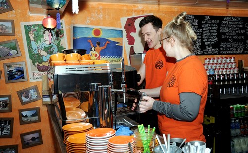 A man and a woman work behind the counter at Nǎm Sông (Five Rivers).