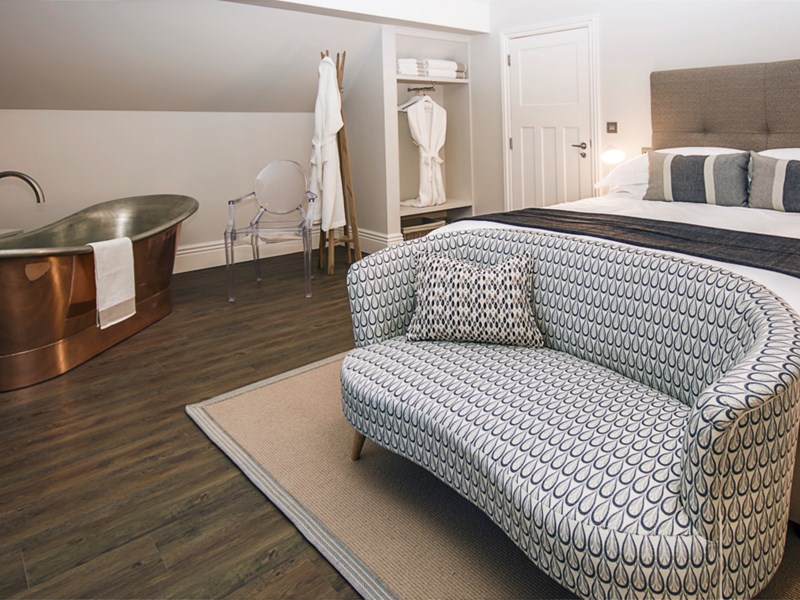 A lavish room at Brocco On The Park, with a double bed, a sofa and a free-standing copper bath.