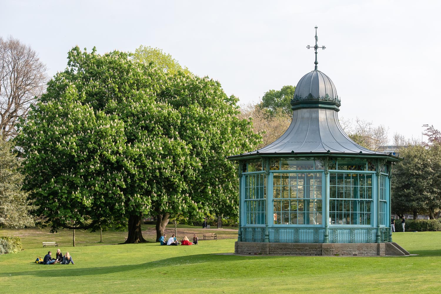 Weston Park bandstand with groups of people sat on the grass to the left.